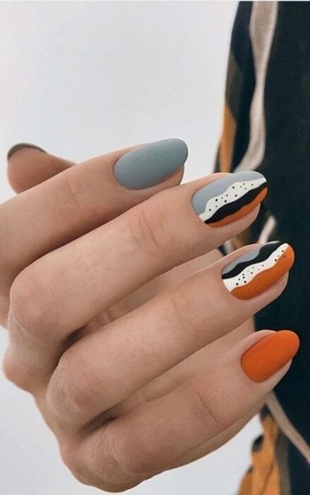 hand with colorful nail design in orange with grayish blue color 