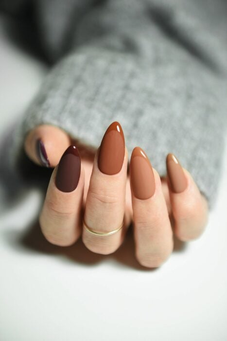 hand of a woman showing her acrylic nails in different shades of brown 