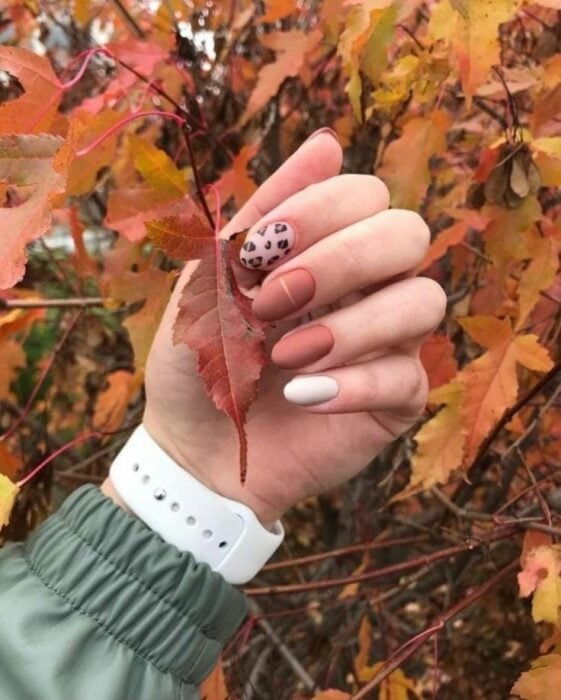 hand showing nail design on some leaves in autumn 