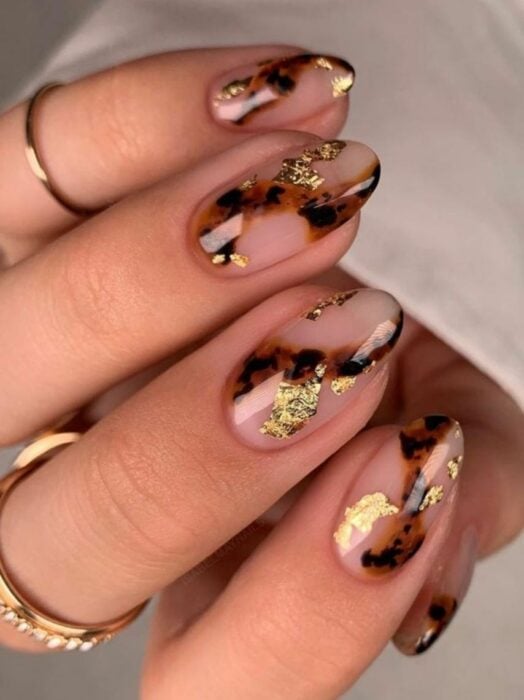 hands showing nail design in coffee color with black and gold leaf 