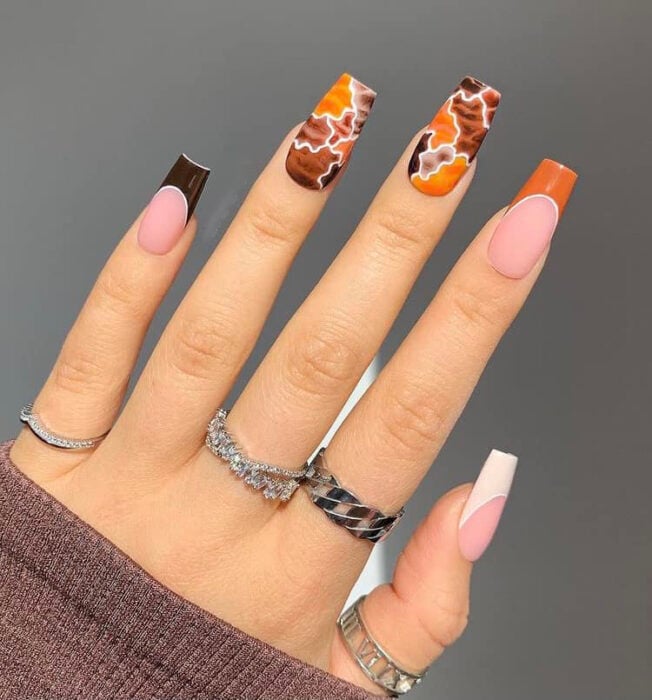 hand showing nail design with puzzle effect in brown and orange colors 