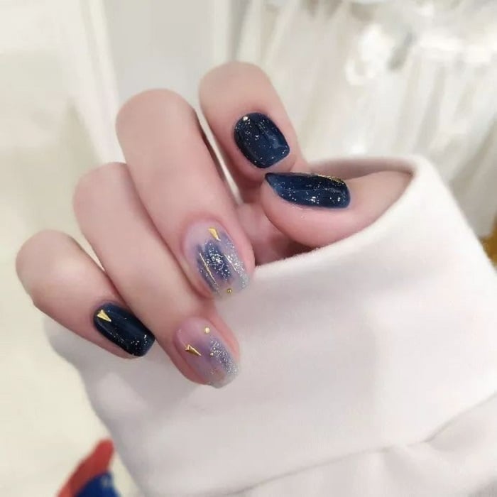 Manicure design in navy and sky blue tones and gold details