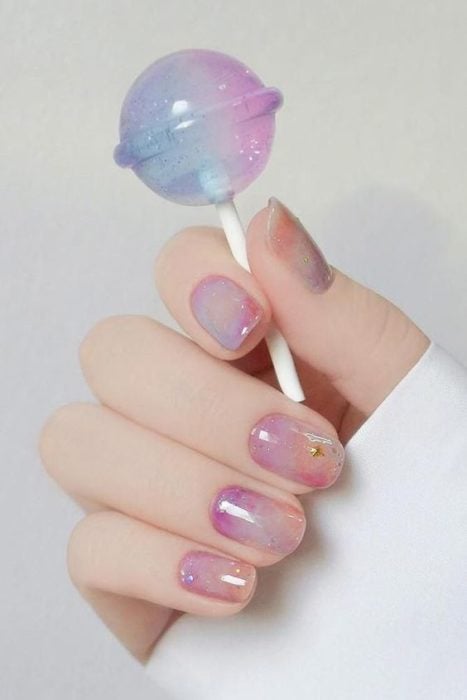 Manicure design in sweet or bubblegum tones and gold-colored figurines